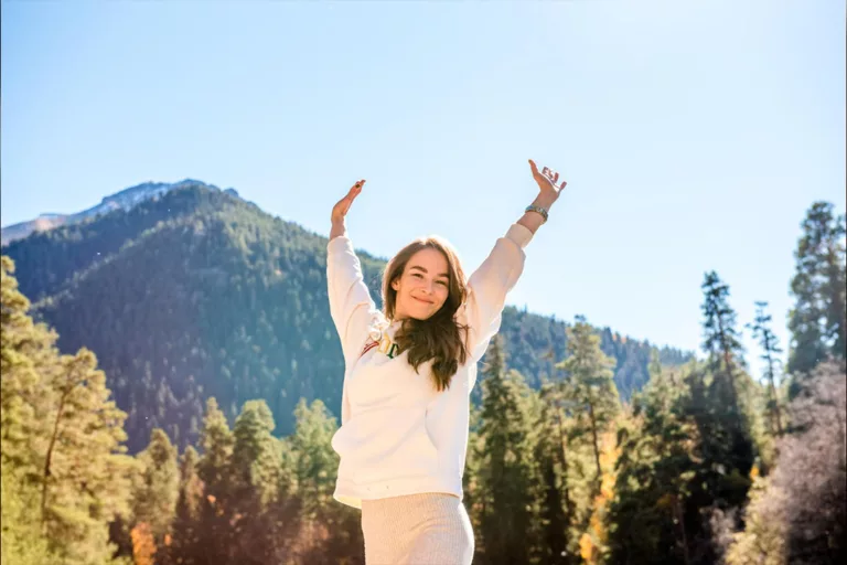 Kobieta radośnie unosząca ręce w górach