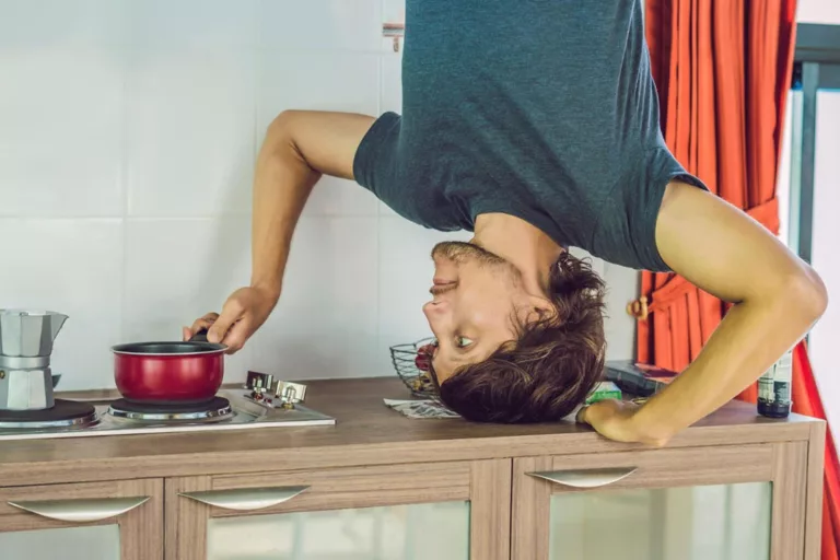 Mężczyzna stojący na głowie na blacie kuchennym w trakcie gotowania w rondlu